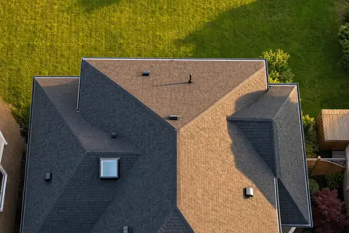 Top-down view of a house with a brand-new charcoal shingle roof at golden hour