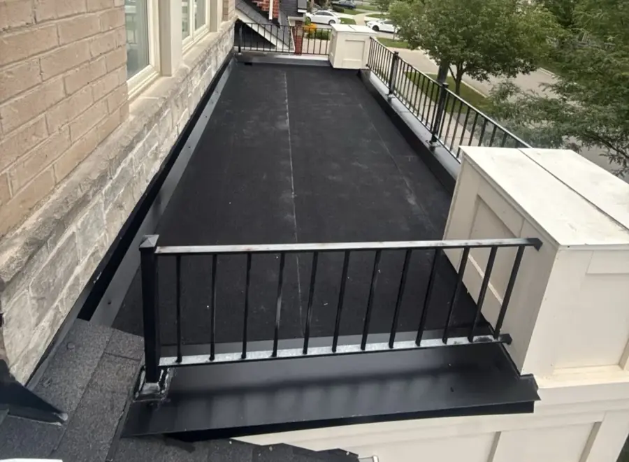 A finished black torch-down balcony roof with a railing in Brampton
