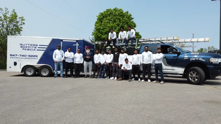 The Real Blue Roofing crew lined up beside their truck and trailer